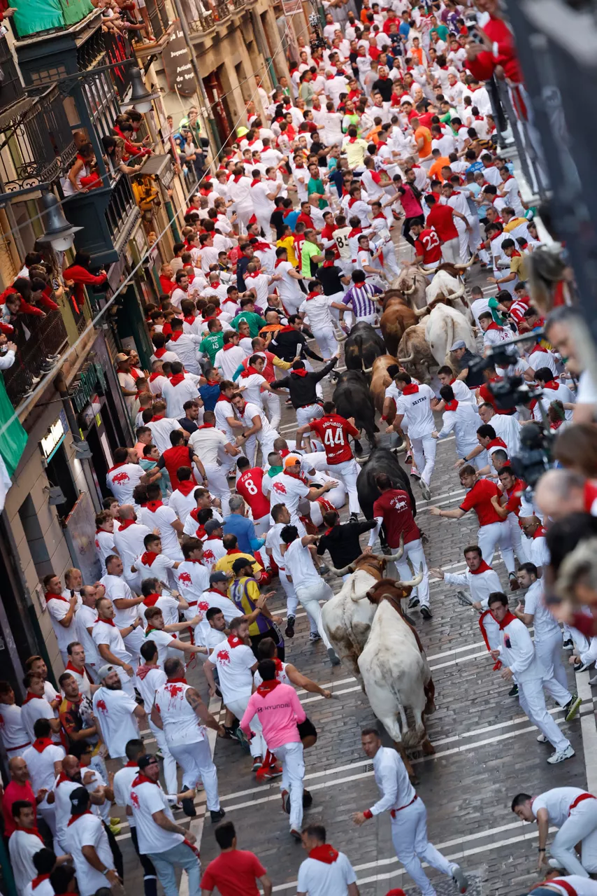 PAMPLONA, 10/07/2025.- Los mozos son perseguido por toros de la ganadería Victoriano del Río Cortés durante el cuarto encierro de los Sanfermines, este jueves, en Pamplona. EFE/Villar López
