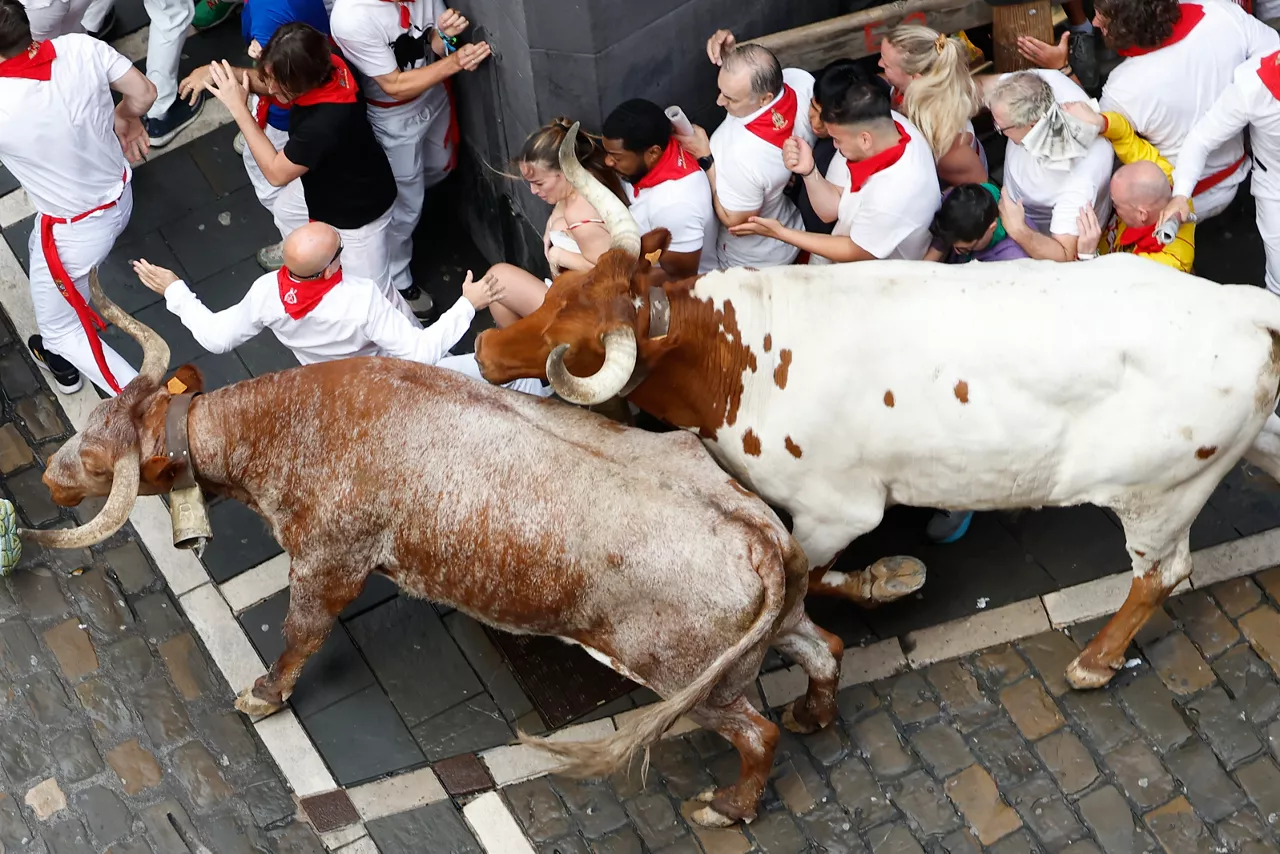 PAMPLONA, 07/07/2025.- Los mozos se arrinconan en una esquina al paso de los toros de la ganadería gaditana de Fuente Ymbro durante el primer encierro de los Sanfermines 2025, este lunes en Pamplona. EFE/Jesús Diges
