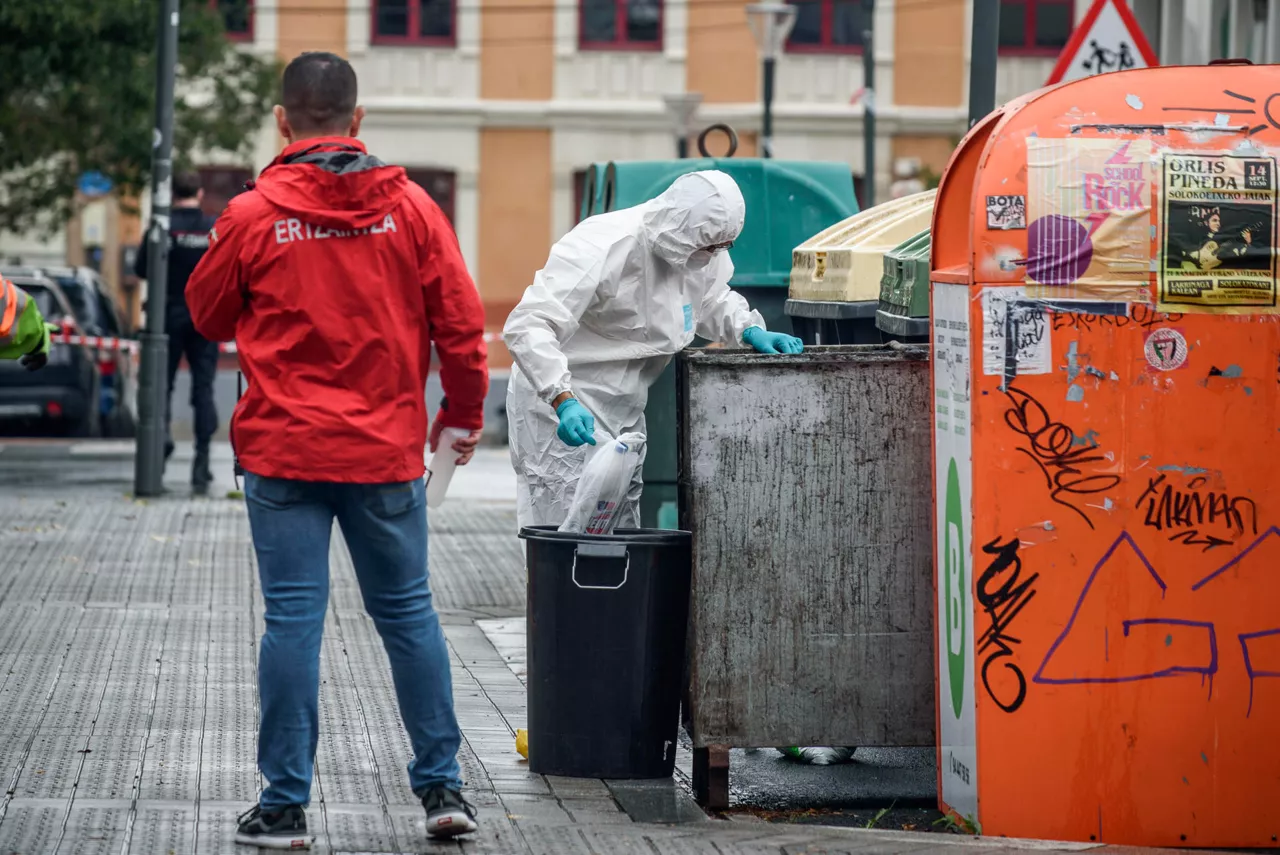 BILBAO (PAÍS VASCO), 21/09/2025.- La Ertzaintza inspecciona unos contenedores cercanos al portal número 7 de la calle Zumarraga de Bilbao, en las investigaciones del fallecimiento de un hombre este domingo en Bilbao tras sufrir heridas de arma blanca en el pecho en el transcurso de un altercado. EFE/Javier Zorrilla
