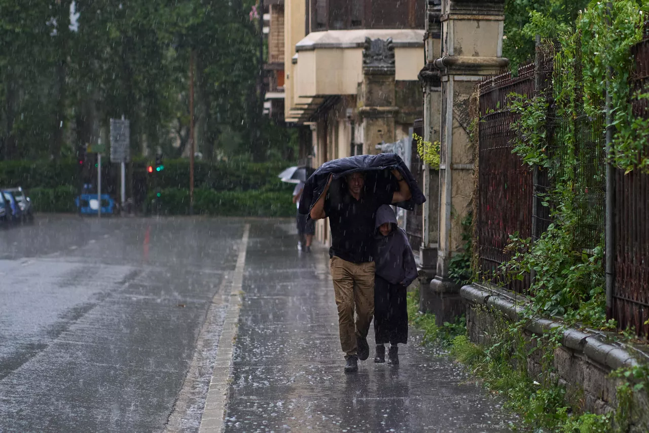 VITORIA, 11/07/20.- Dos personas se refugian de la lluvia y el granizo caido hoy viernes en Vitoria por el paso de la DANA por el norte del pais. EFE/ADRIAN RUIZ HIERRO
