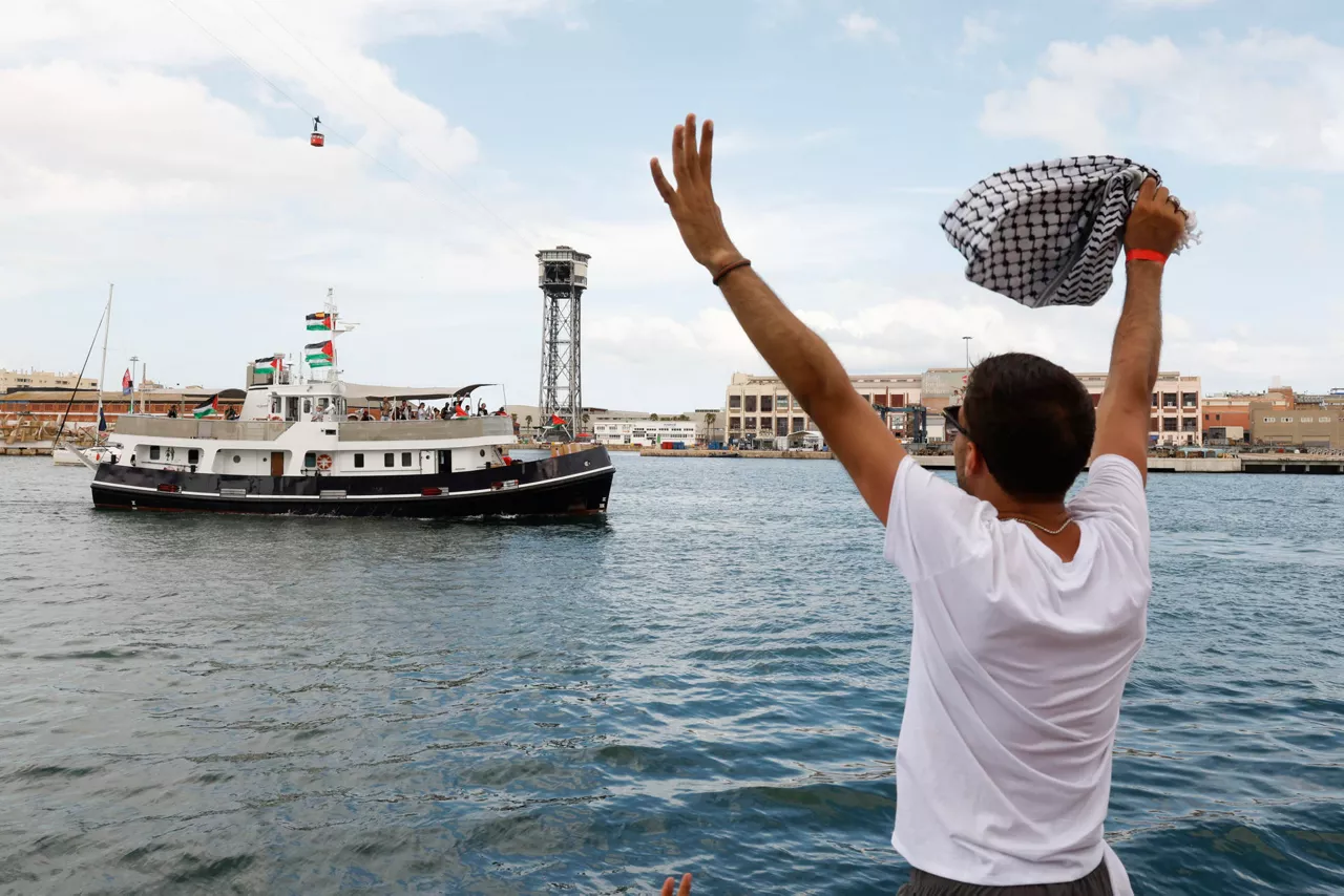 BARCELONA, 31/08/2025.- Un hombres despide a los barcos que forman parte de la flotilla en el puerto de Barcelona este domingo. La flotilla Global Sumud sale este domingo desde Barcelona y con destino a Gaza, en una acción solidaria con el pueblo palestino en la que participan entidades de 44 países. EFE/ Toni Albir
