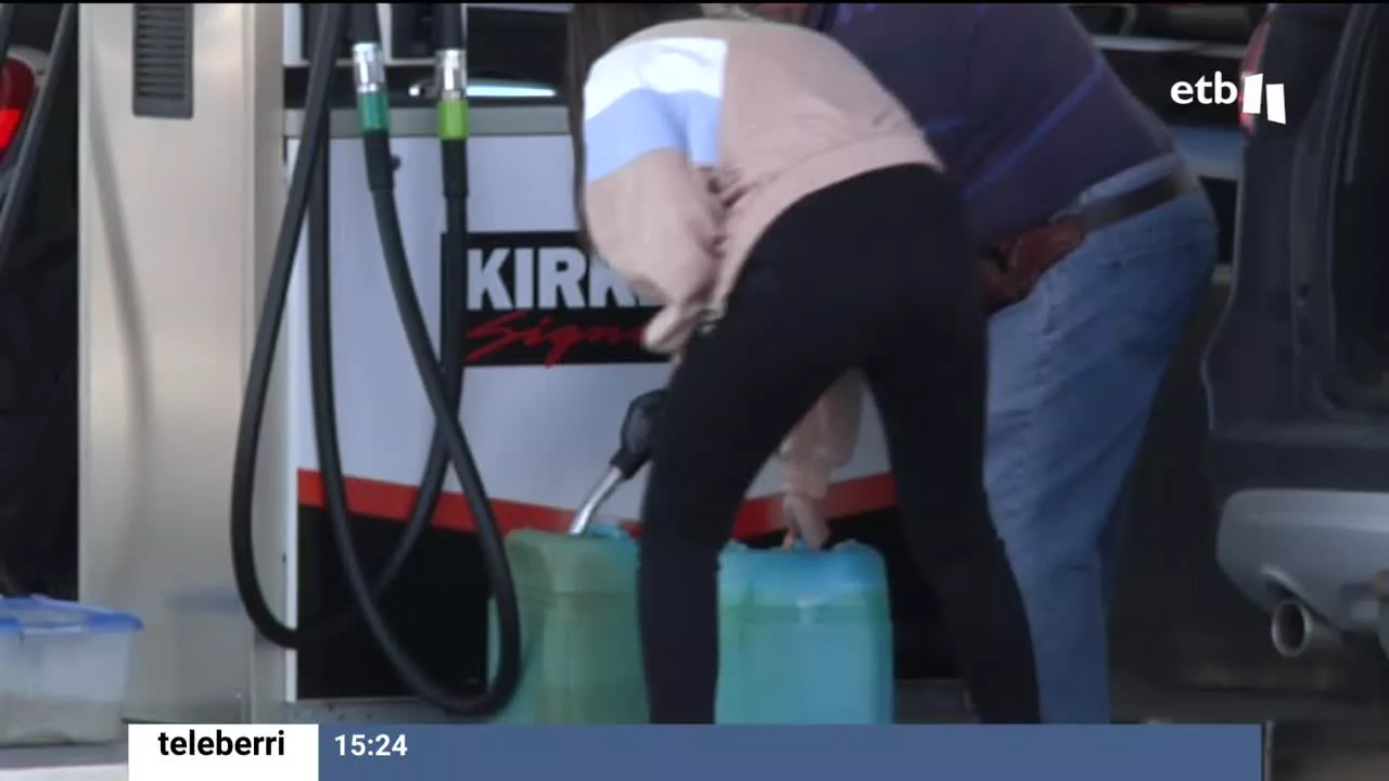 Dos personas llenan bidones con combustible.