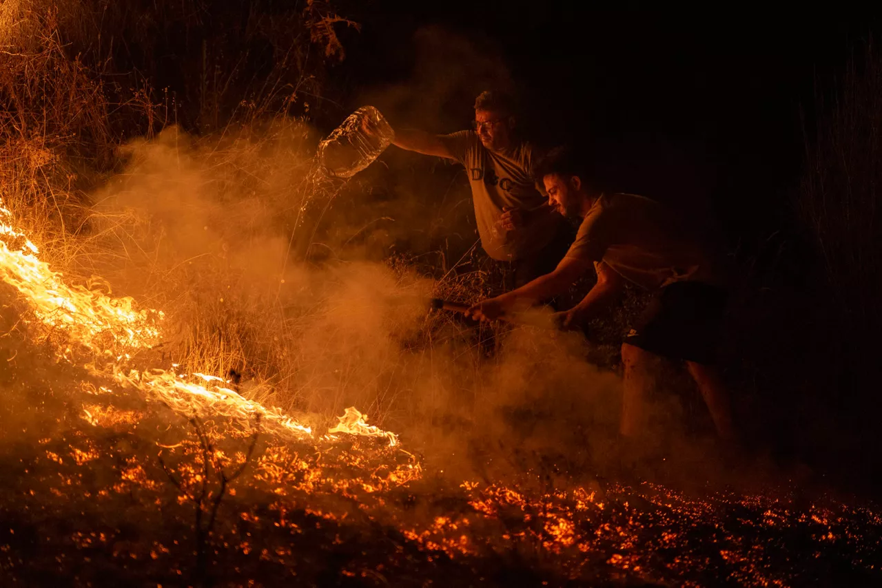 A RÚA (OURENSE), 17/08/2025.- Vecinos de la localidad trabajan la madrugada de este domingo en labores de extinción del incendio forestal de A Rúa (Ourense). Los incendios han calcinado más 50.000 hectáreas, la mayoría en la provincia de Ourense, la más castigada por el momento y en la que se han reactivado fuegos en las últimas horas. EFE/ Brais Lorenzo
