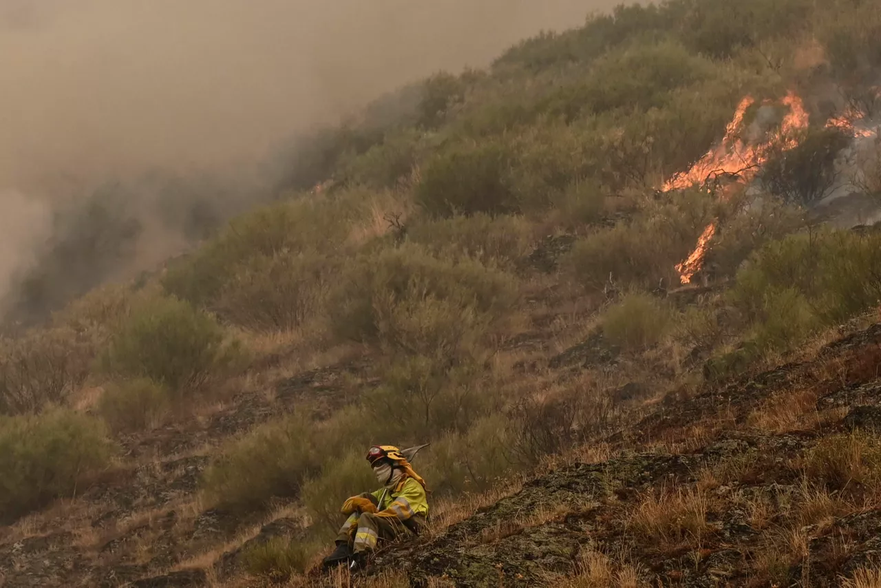 BARNIEDO DE LA REINA (LEÓN), 18/08/2025.- Una persona que lucha contra el fuego muestra su desesperación ante el incendio que amenaza la vertiente leonesa del Parque Nacional de Picos de Europa, iniciado en Barniedo de la Reina e impulsado por el viento y las altas temperaturas. EFE/J.Casares
