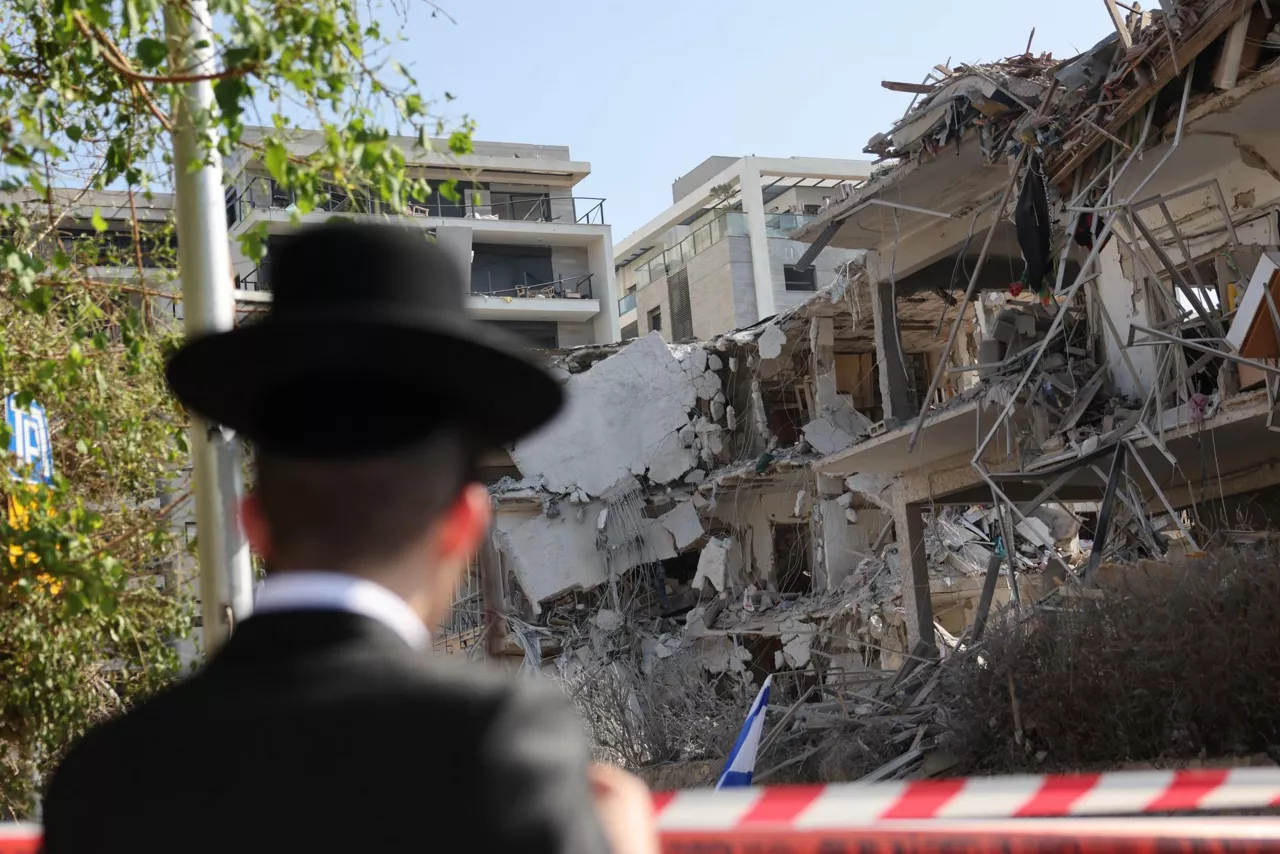 Tel Aviv (Israel), 14/06/2025.- A person stands near a damaged residential building after a ballistic missile strike in Tel Aviv, Israel, 14 June 2025. Israel's military said Iran launched dozens of missiles and drones toward Israel, with some intercepted. Magen David Adom (MDA), Israel's national emergency services, reported at least three killed and dozens of injured, including some in critical condition, in the retaliatory attacks. Israel launched strikes on Iran's nuclear and military facilities on 13 June, targeting top generals and scientists. EFE/EPA/ABIR SULTAN
