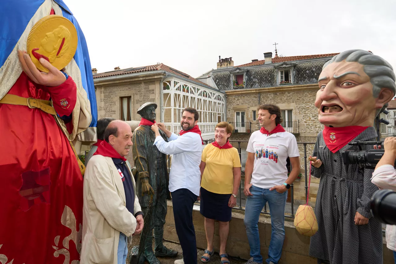 GRAFCAV9869. VITORIA (ESPAÑA), 07/07/2025.- El portavoz municipal del PP, Iñaki García Calvo (2i), ha presentado este lunes a las personas elegidas por su formación para disparar el chupinazo de las fiestas de la Blanca de Vitoria. En la imagen el concejal le coloca el pañuelo de las fiestas a la escultura del Celedón, personaje principal de las fiestas de la capital alavesa. EFE/ADRIAN RUIZ HIERRO
