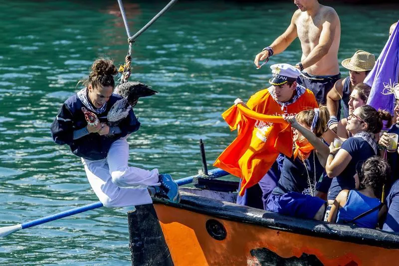 Una participante se lanza a por el ganso desde una embarcación