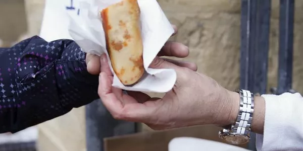 La vendedora de un puesto entrega un bocadillo de txistorra en la plaza de