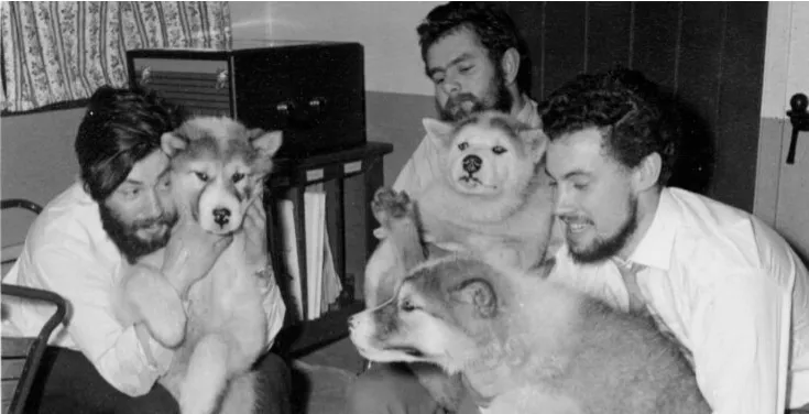 Dennis Bell (ezkerrean) lankideekin eta Antartikan lan egiten lagundu zieten txakurrekin, 1959ko neguaren erdialdera, Admiralty Bay Base-n. Argazkia: British Antartic Survey.