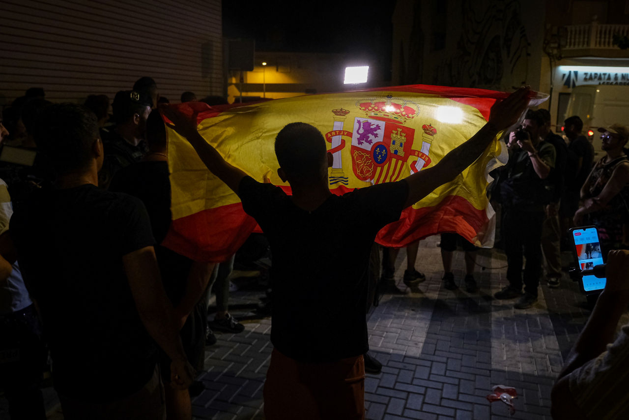 TORRE PACHECO (MURCIA), 15/07/2025.- Un manifestante ondea una bandera de España mientras increpa a periodistas este martes en Torre Pacheco (Murcia). La Guardia Civil ha impedido la manifestación prevista para las 20:00 horas a las puertas del Ayuntamiento de Torre Pacheco para evitar altercados ante la presencia de grupos ultra en la población. Según fuentes cercanas al instituto armado consultadas por EFE, los agentes están invitando a los asistentes a abandonar la zona, en la que se encontraban varias decenas de personas convocadas bajo el lema "Solo el pueblo salva al pueblo". EFE/ Pablo Miranzo
