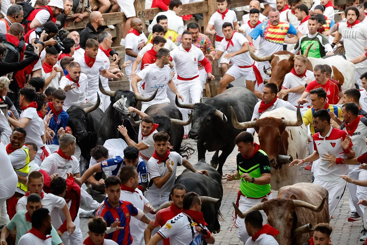 PAMPLONA, 14/07/2025.- Los mozos son perseguidos por toros de la ganadería sevillana de Miura durante el octavo y último encierro de los Sanfermines este lunes. cumplen con la tradición y ponen el broche este 14 de julio, un año más, a los encierros de los Sanfermines. EFE/ Villar López
