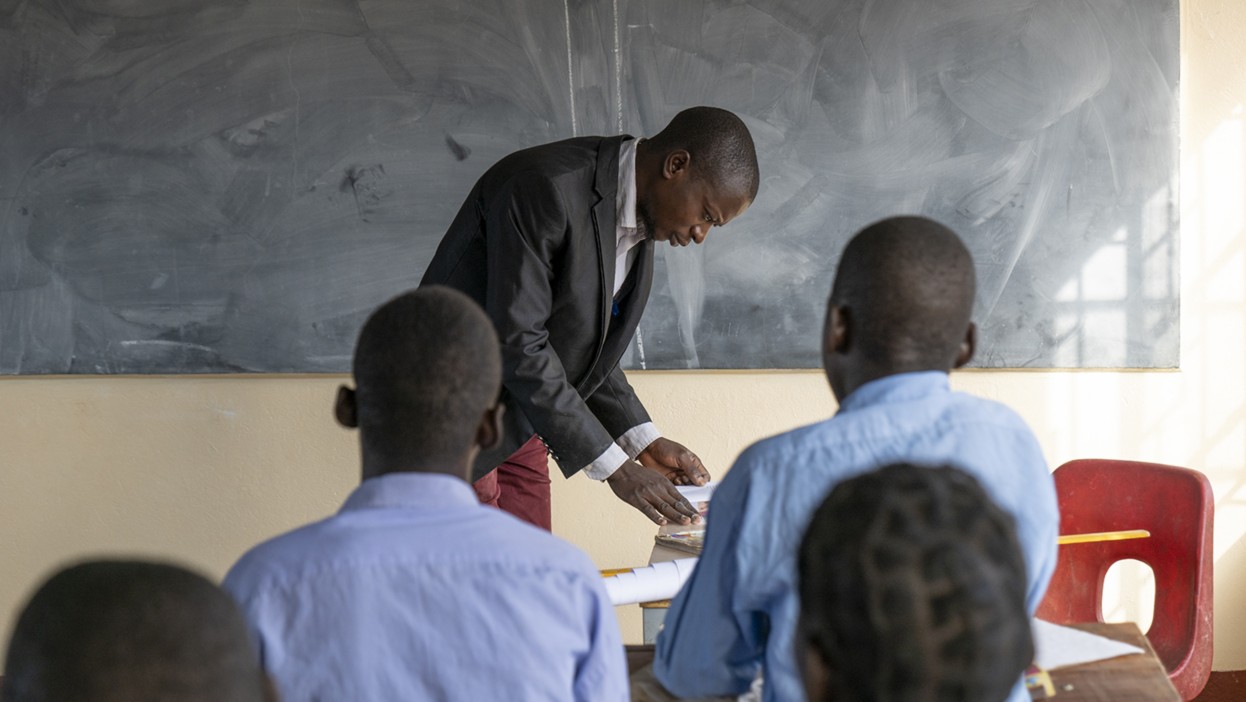 un insegnanete alla lavagna e un gruppo di ragazzi che ascoltano