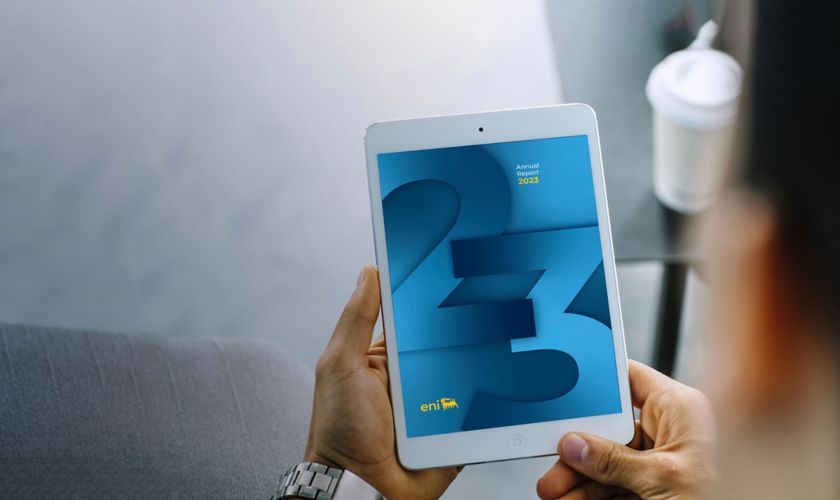 Hand with iPad looking at graphic cover of the Eni 2023 interactive budget