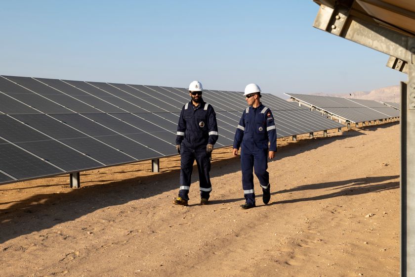 Due uomini parlano camminano nell’impianto di pannelli solari nel deserto egiziano