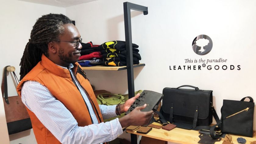 Uomo africano sistema le borse di pelle all'interno del suo negozio