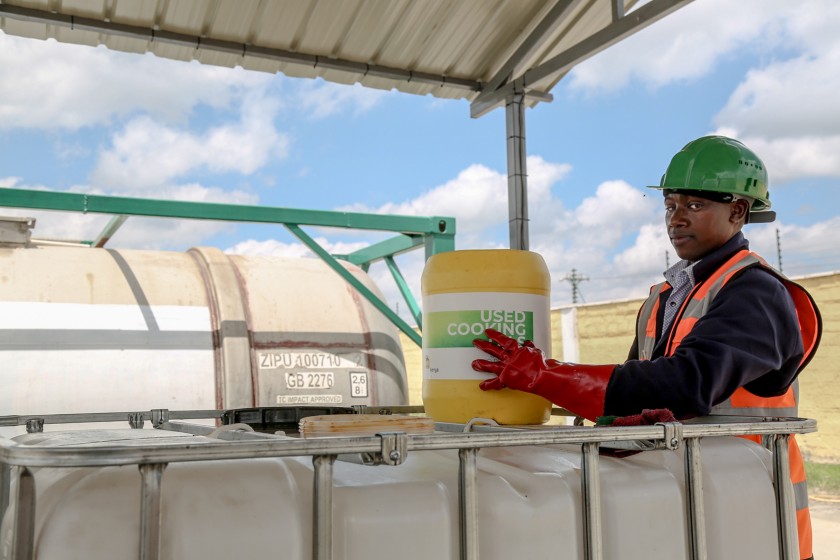 Operaio africano con in mano un contenitore di olio esausto