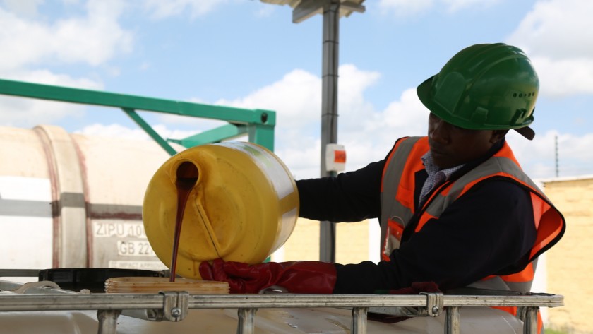 Operaio africano sistema contenitori di oli di cucina esausti