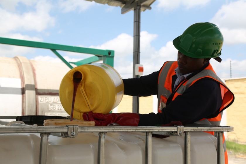 Operaio africano sistema contenitori di oli di cucina esausti