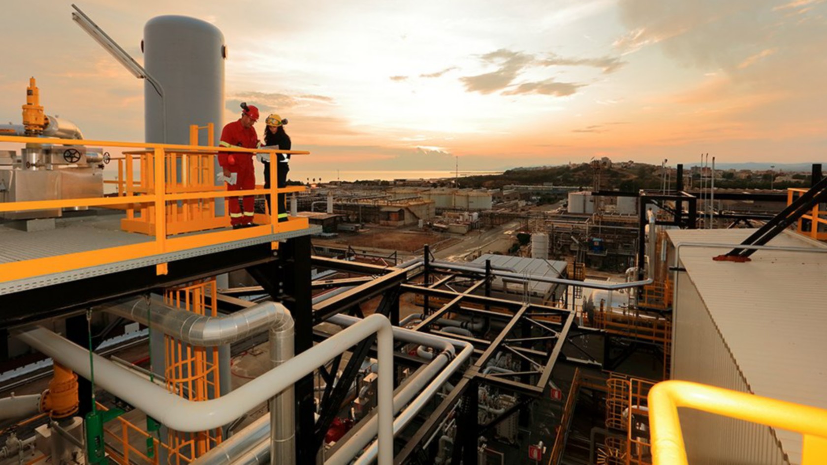 Vista dell'impianto di Gela al tramonto con due operai