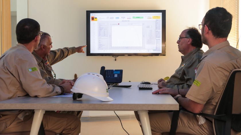 Team workers sitting around the table monitor the progress of the plant, looking at the screen