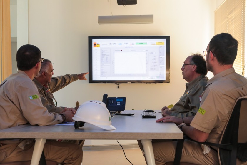 Team workers sitting around the table monitor the progress of the plant, looking at the screen