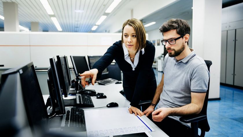 Due colleghi a lavoro in ufficio controllano dati al computer