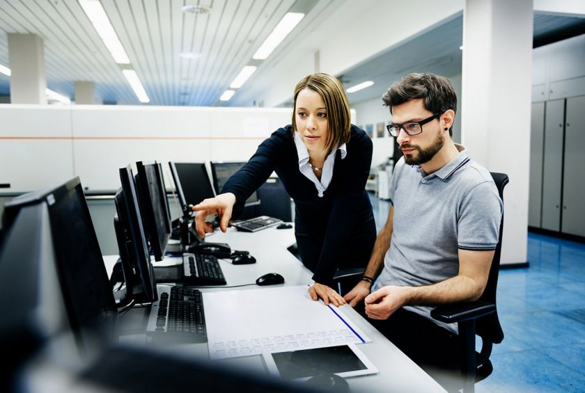 Due colleghi a lavoro in ufficio controllano dati al computer