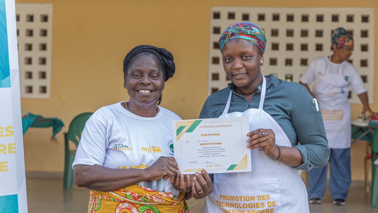 Two women show their certificates from a course on improved stoves