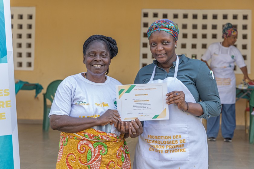 Two women show their certificates from a course on improved stoves