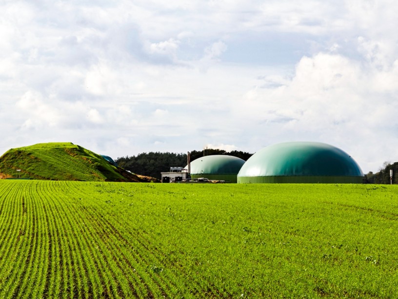 Vista della centrale di biometano circondata da natura sotto un cielo nuvoloso