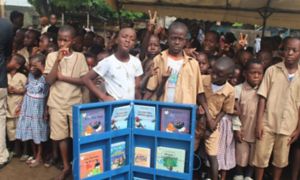 African children posing in front of a display case of books