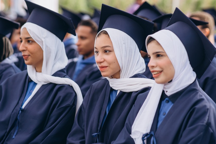 Three female students sitting next to each other during the end-of-course ceremony