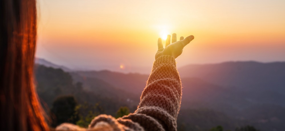 Donna che guarda l'orizzonte con la luce del sole tra le mani