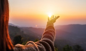 Donna che guarda l'orizzonte con la luce del sole tra le mani