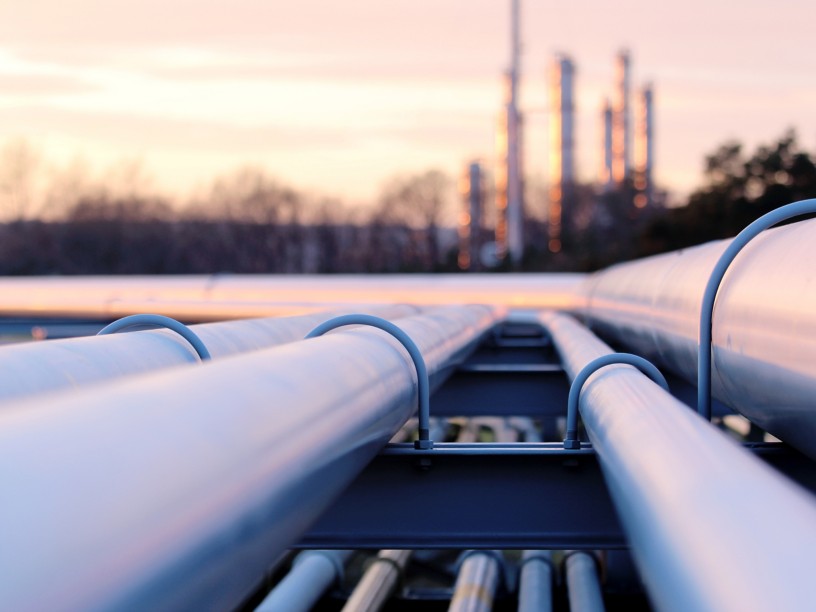 Gas pipes at sunset with chimneys in the background
