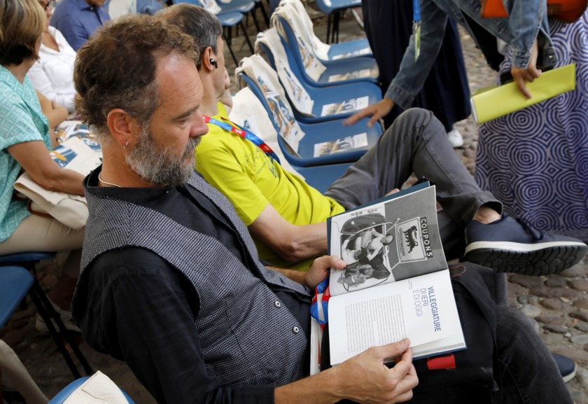 Un uomo seduto del pubblico sfoglia una rivista durante l'evento