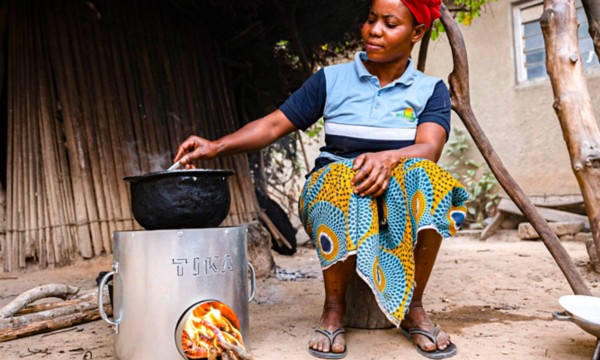 Donna africana  cucina pietanza con il fornello appoggiato a terra