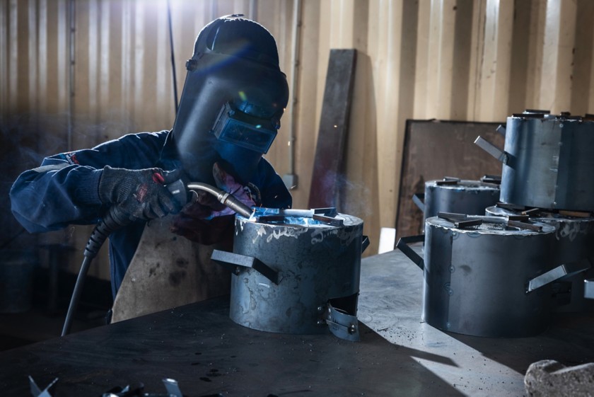A man is manufacturing improved cookstoves.