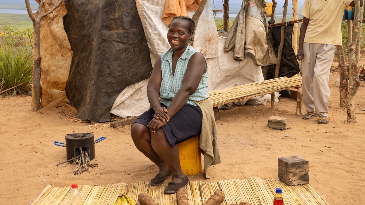 A woman sits and a man stands near a rural home in Angola