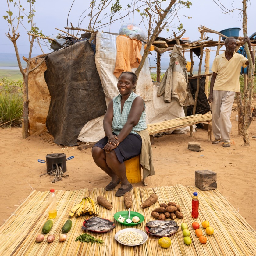 A woman sits and a man stands near a rural home in Angola