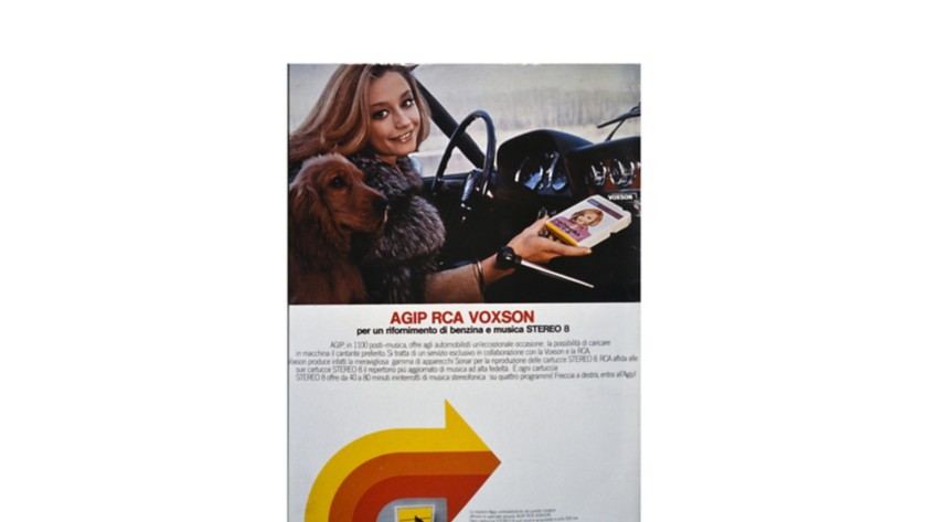 Raffaella Carrà at the wheel with the yellow, orange, and red arrow from the Agip advertising campaign below