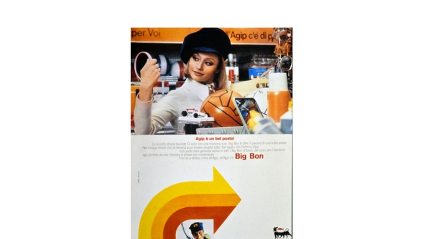 Raffaella Carrà in an Agip station looks at items for sale with the yellow, orange, and red Agip arrow below