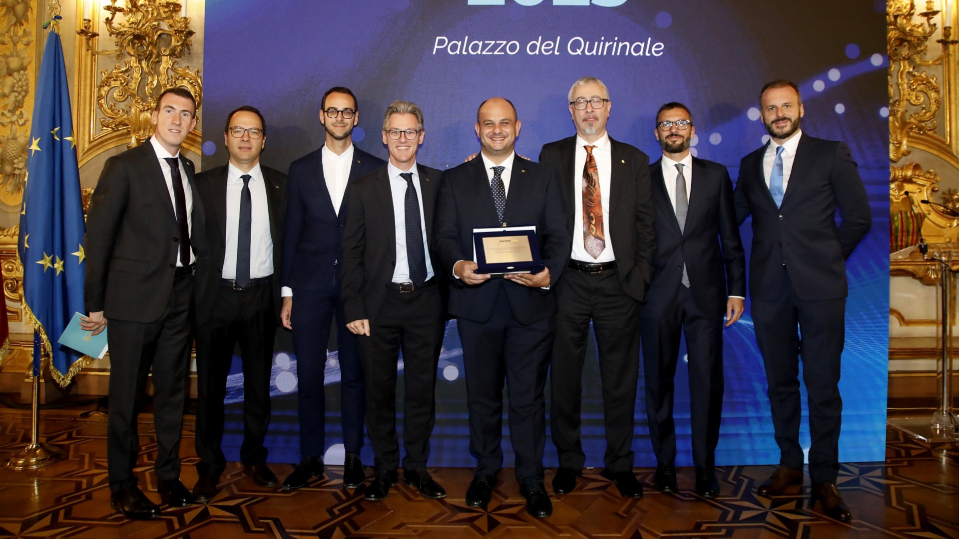 Simone Ambrosini, Michele Gerolin, Tiberio Grasso, Luigi Miozza, Alberto Moro e Andrea Vignali, vincitori del "Premio Riconoscimento all’Innovazione Eni", posano in piedi con la targa dell’’Eni Award