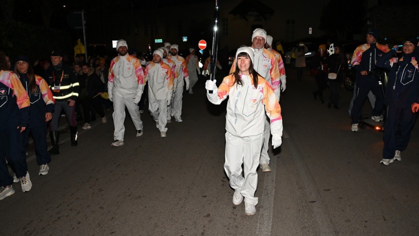 La torcia Olimpica, sorretta da una tedofora, sfila nella tappa di Viggiano del Viaggio della Fiamma Olimpica, accompagnata dai tedofori.