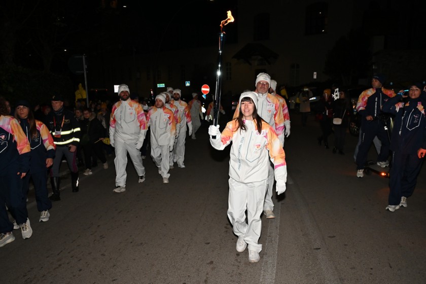 La torcia Olimpica, sorretta da una tedofora, sfila nella tappa di Viggiano del Viaggio della Fiamma Olimpica, accompagnata dai tedofori.