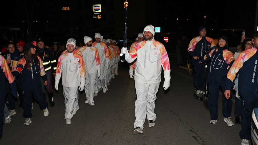 La torcia Olimpica, sorretta da un tedoforo, sfila nella tappa di Viggiano del Viaggio della Fiamma Olimpica, accompagnata dai tedofori.