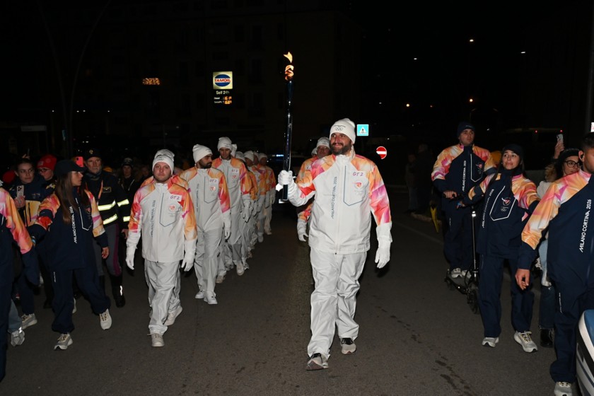 La torcia Olimpica, sorretta da un tedoforo, sfila nella tappa di Viggiano del Viaggio della Fiamma Olimpica, accompagnata dai tedofori.