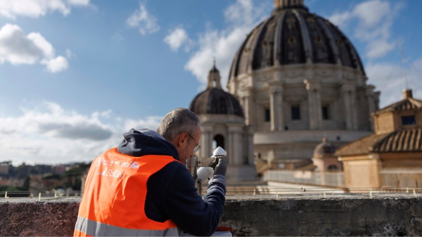 Tecnico opera su un tetto esterno del Vaticano con cupola di San Pietro sullo sfondo