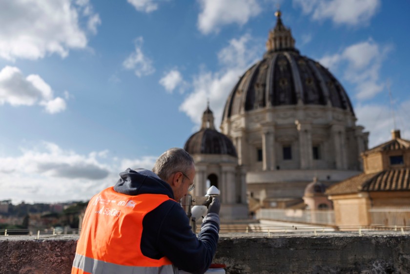 Tecnico opera su un tetto esterno del Vaticano con cupola di San Pietro sullo sfondo