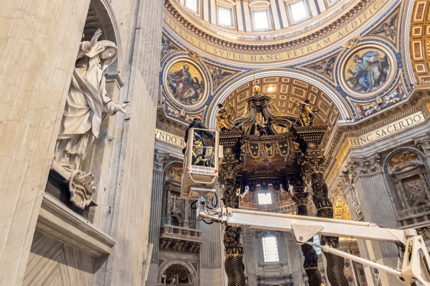 Un operatore su una piattaforma aerea lavora vicino alle colonne del Baldacchino di Bernini 